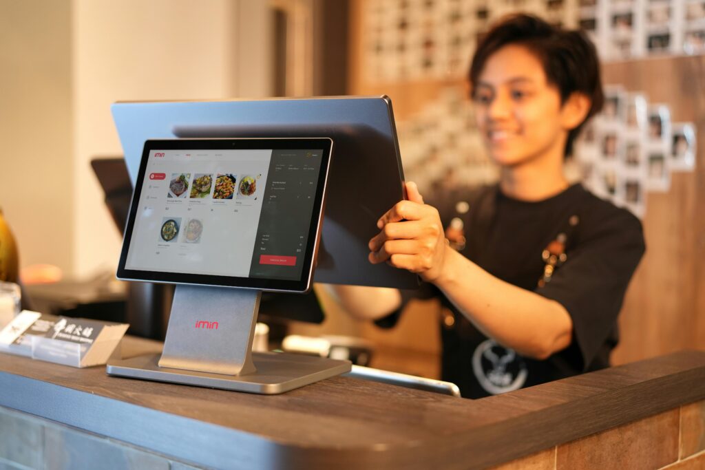 /business-application-form Smiling cashier using a touchscreen POS system in a modern retail environment.
