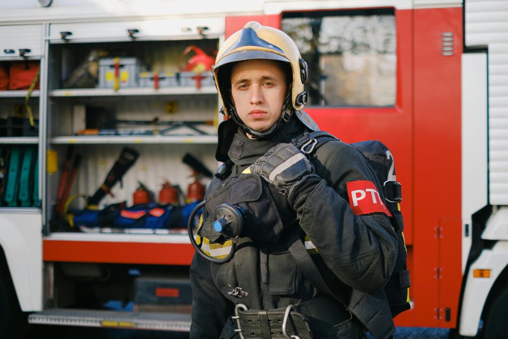 Healthcare & Fire Department Program A firefighter in uniform stands confidently next to a fire truck, showcasing readiness.